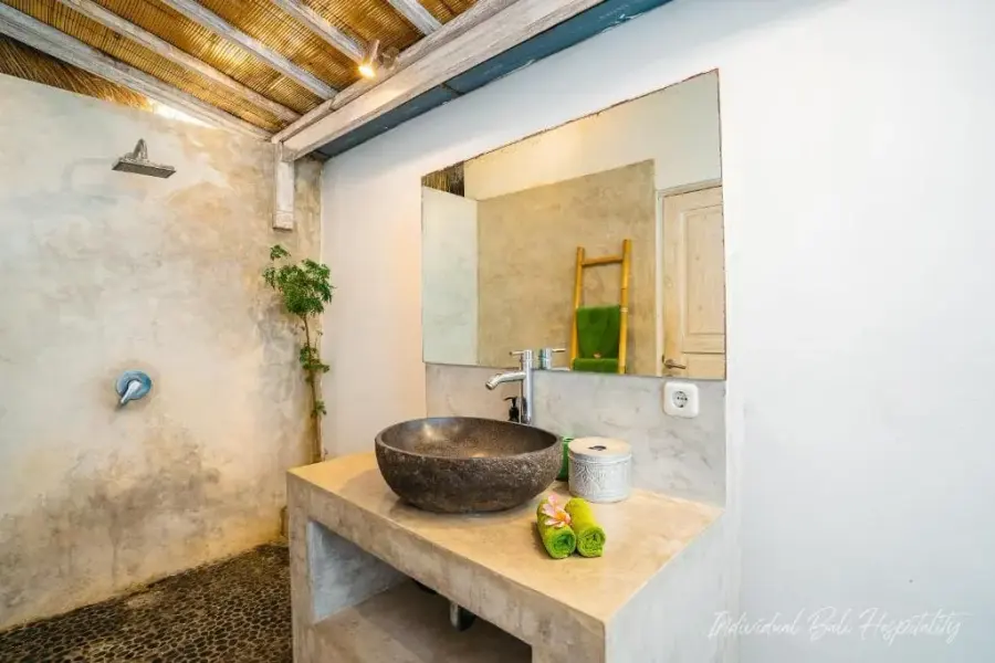 A river-stone bathroom, ladder of green towels