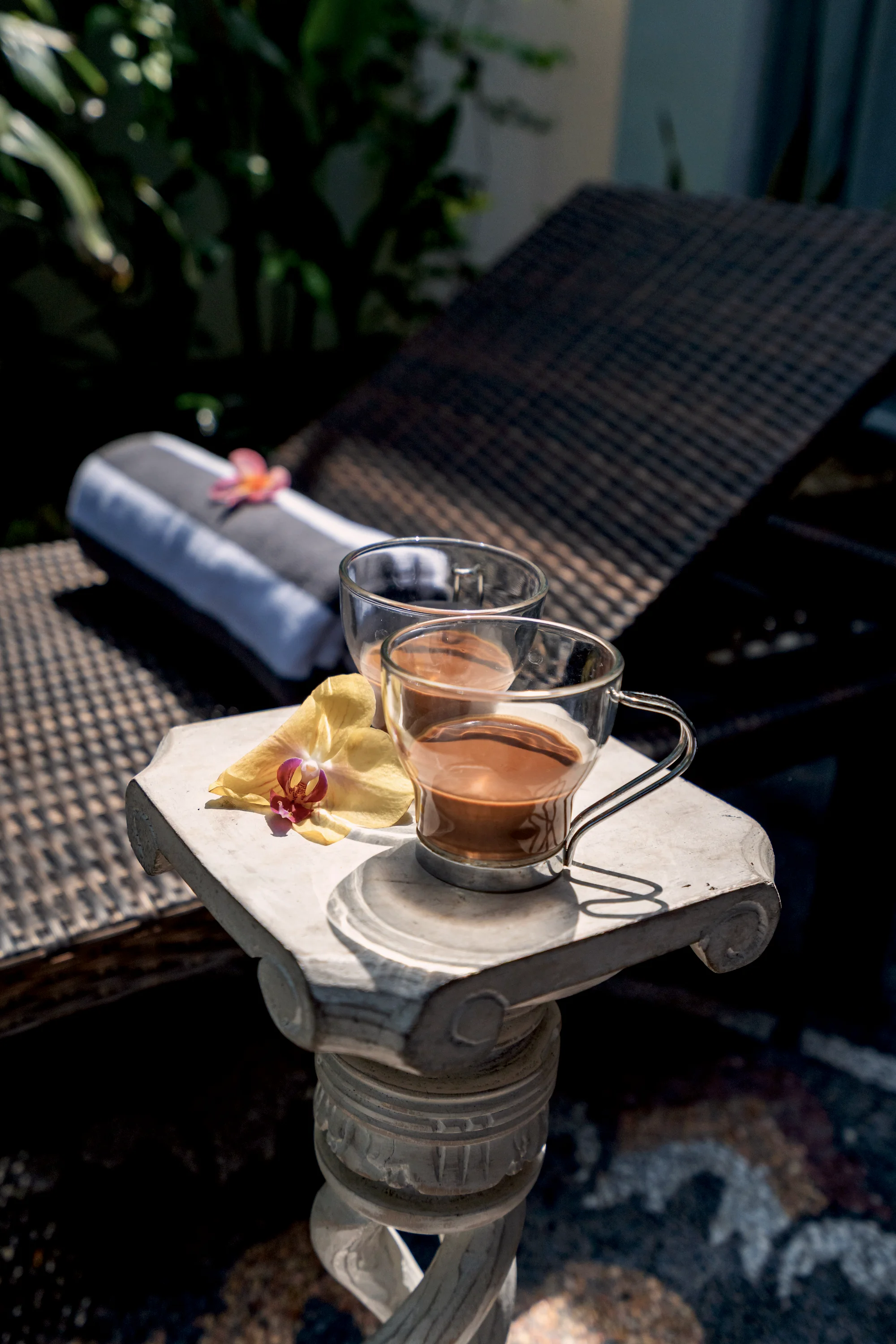Two glasses of tea on a carved stone tray beside a lounger