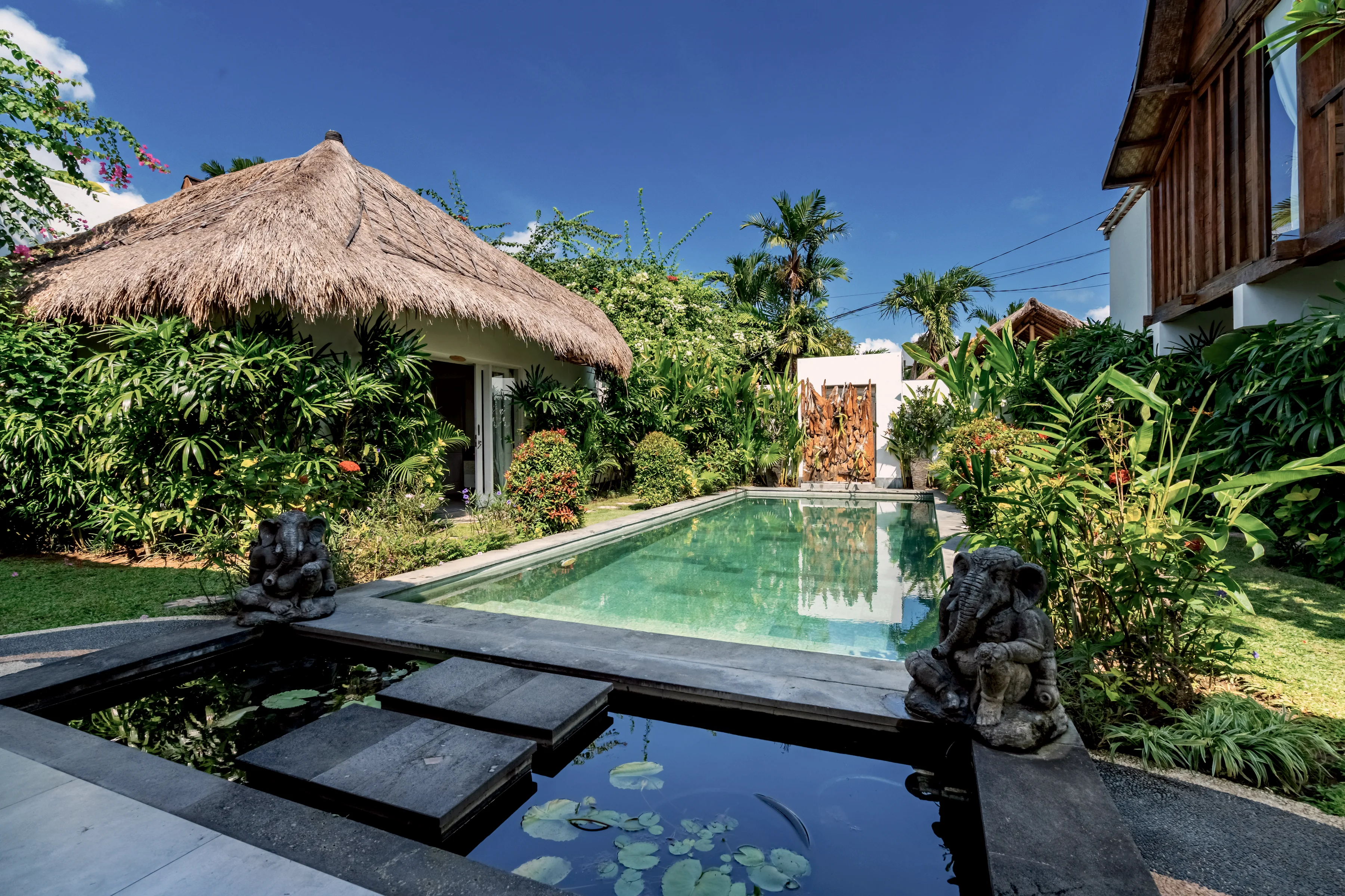 Stepping slabs across the lily pond to the pool, with stone statues on either side