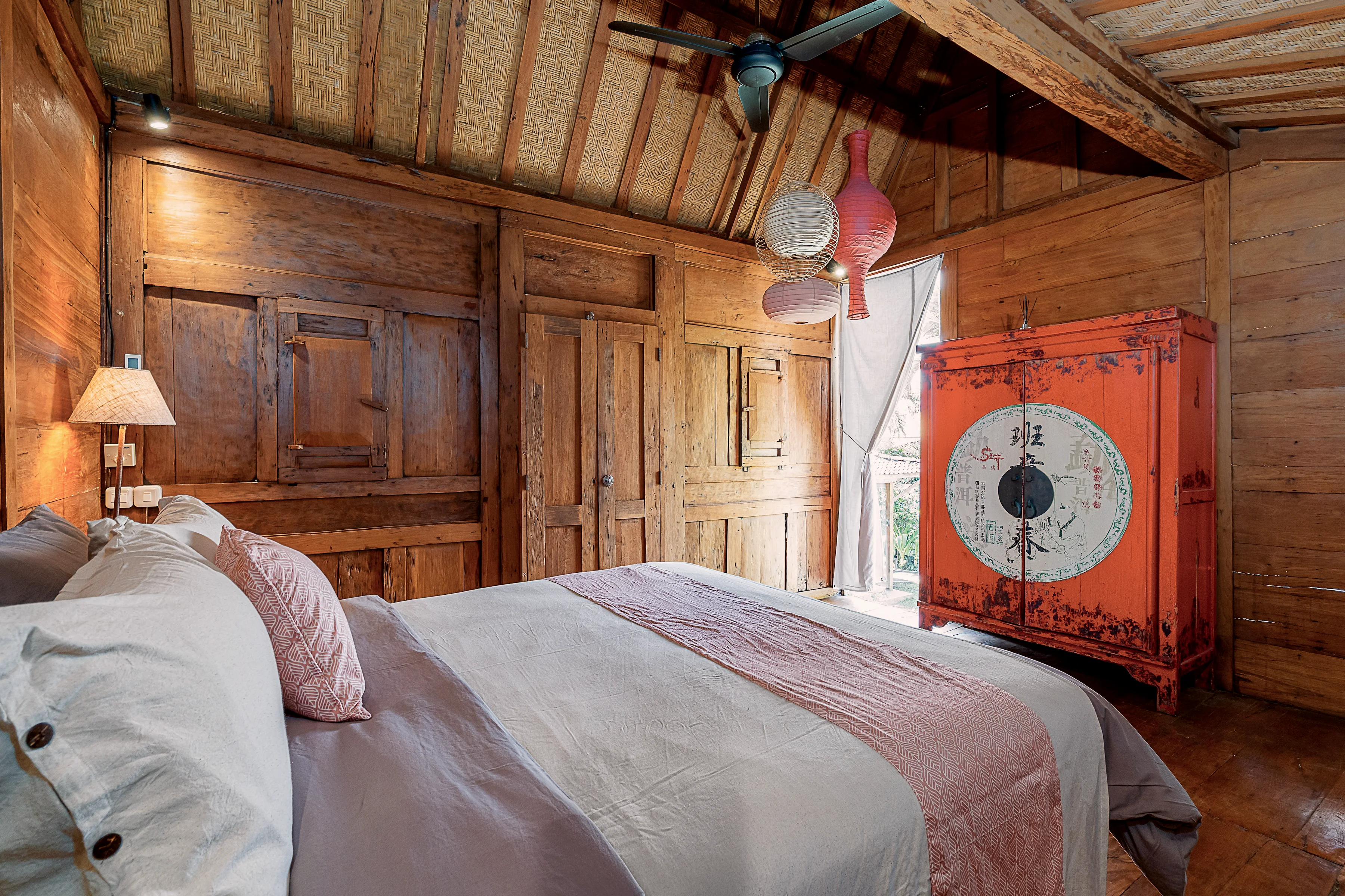 A Joglo bedroom with a red lacquered chest against the panelled wall