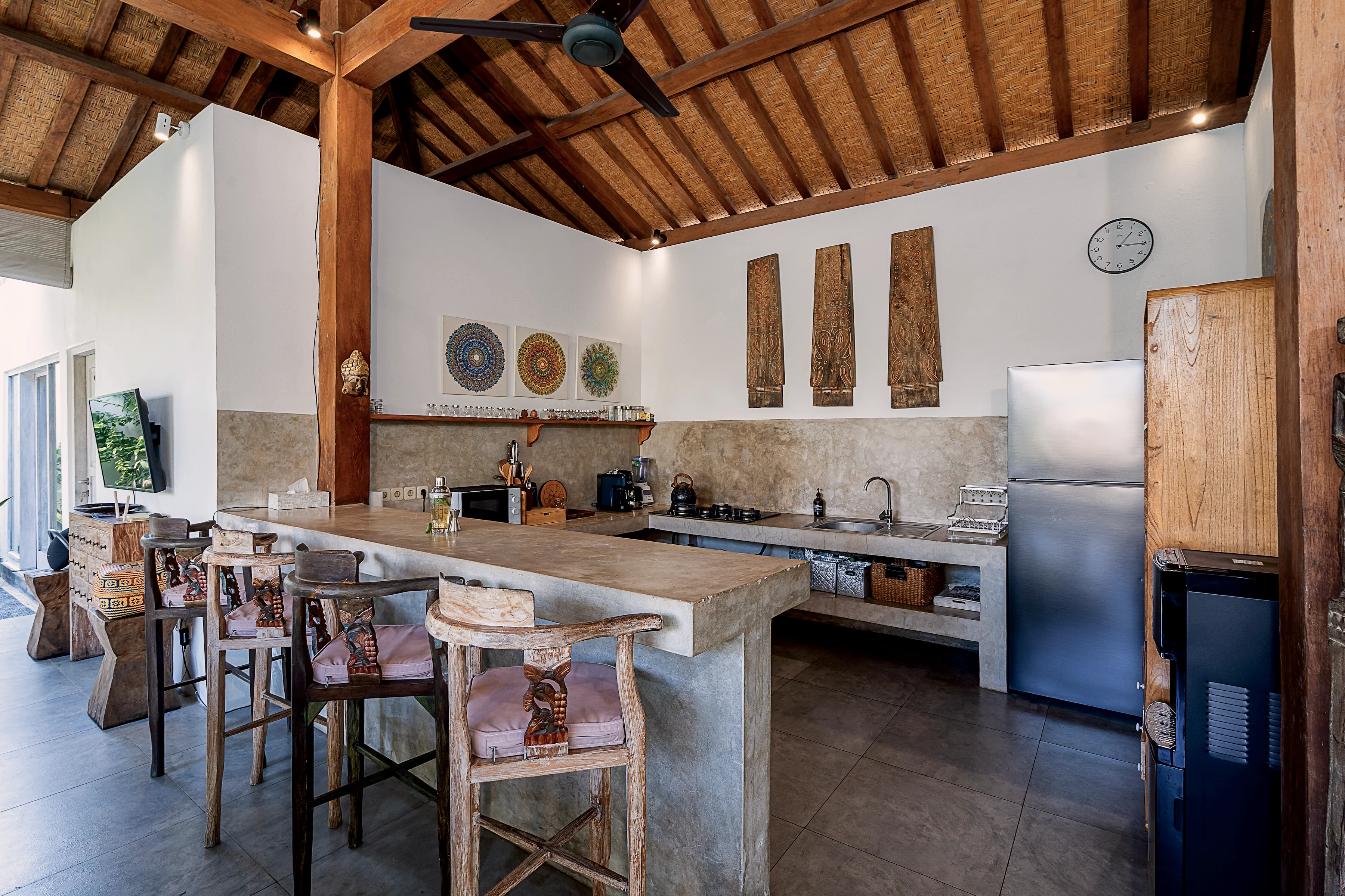 The kitchen island with stools, fridge and worktop under the timber roof