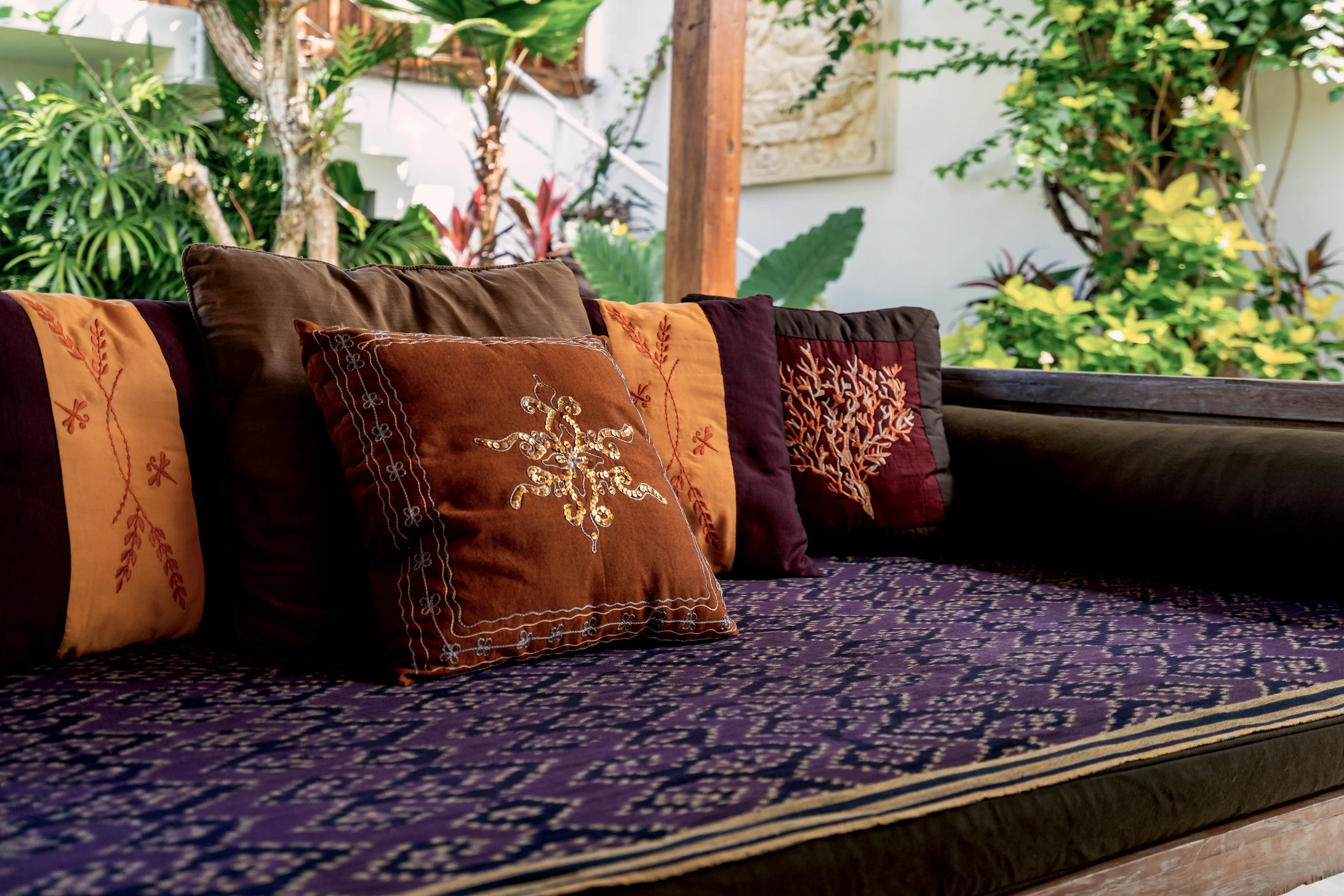 Embroidered cushions on a purple woven daybed
