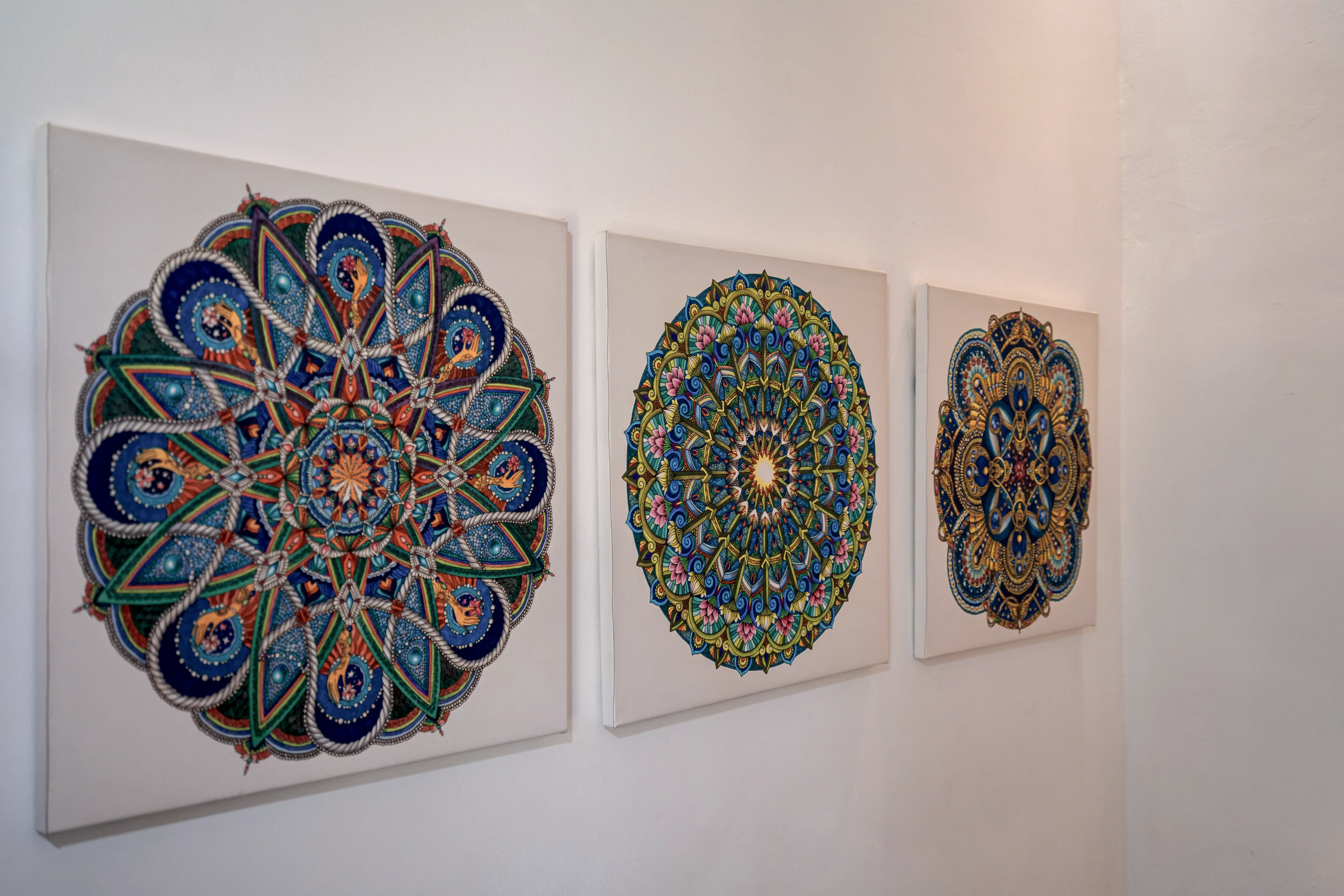 Three painted mandala plates on a white wall