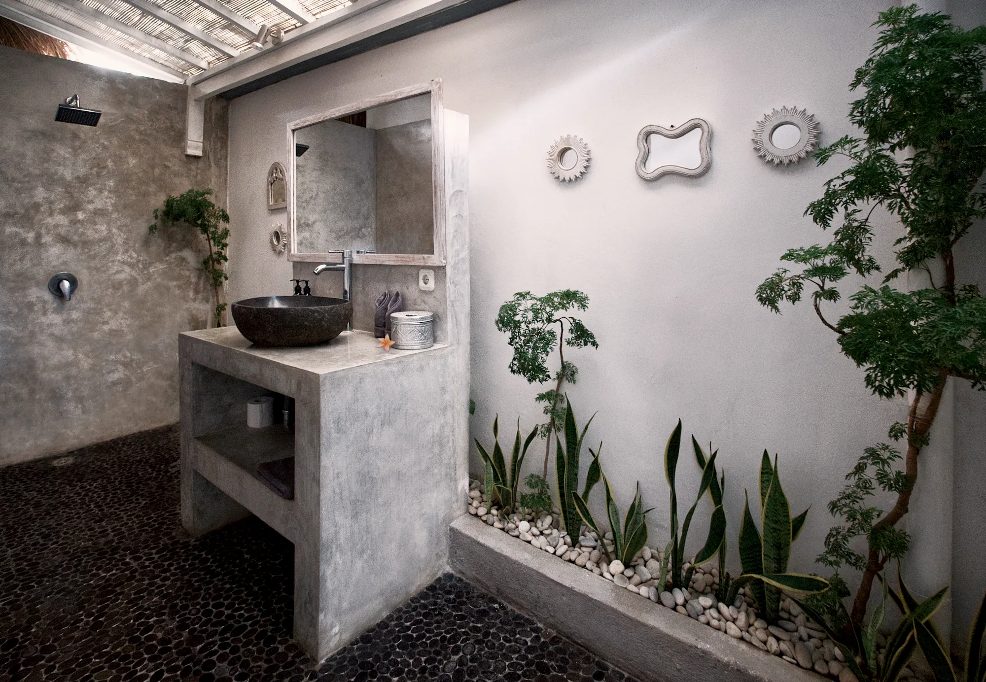 The master bathroom: a stone basin, a pebble floor and plants along the wall