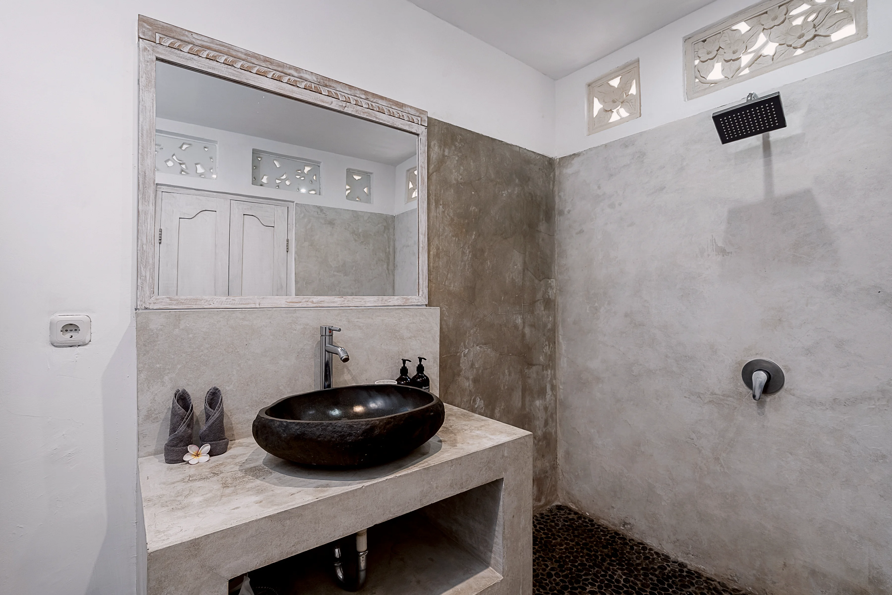 A rain shower and a stone basin under carved vents