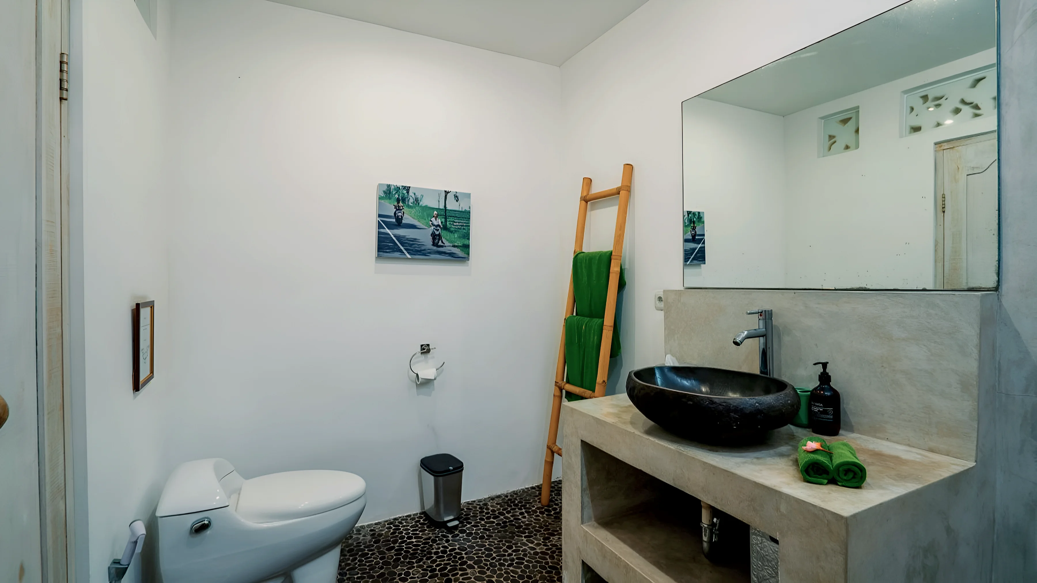 A bathroom with a stone basin, a mirror and a towel ladder