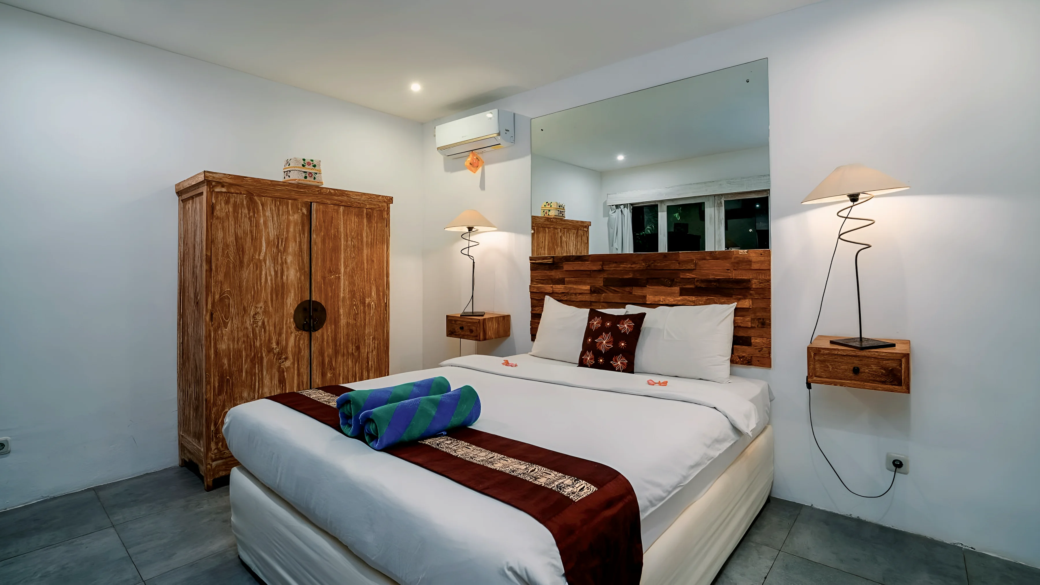 A white bedroom with a teak wardrobe and a double bed