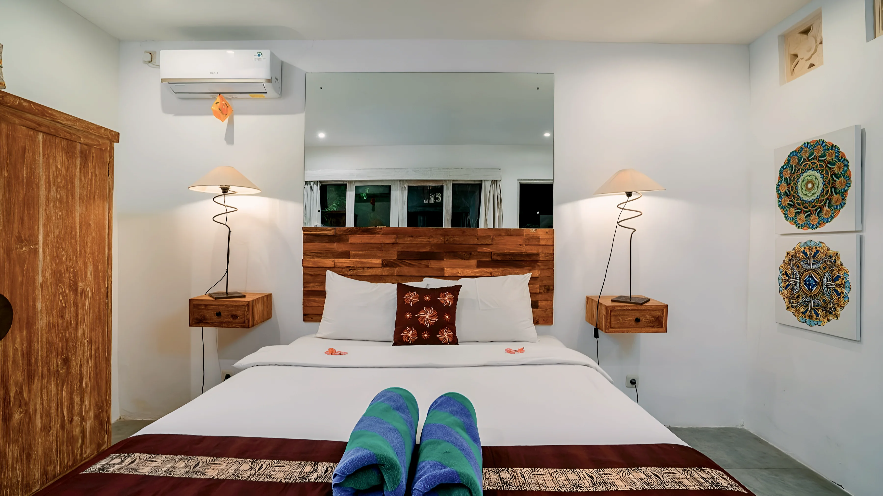 A double bed with folded towels and painted plates on the wall