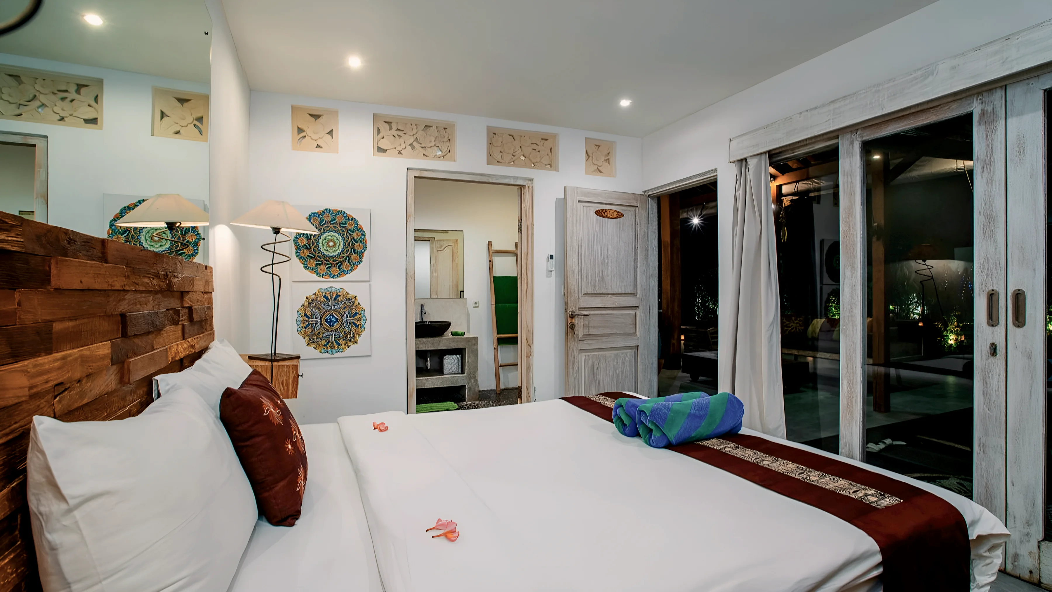 A bedroom with a carved headboard and glass doors to the garden