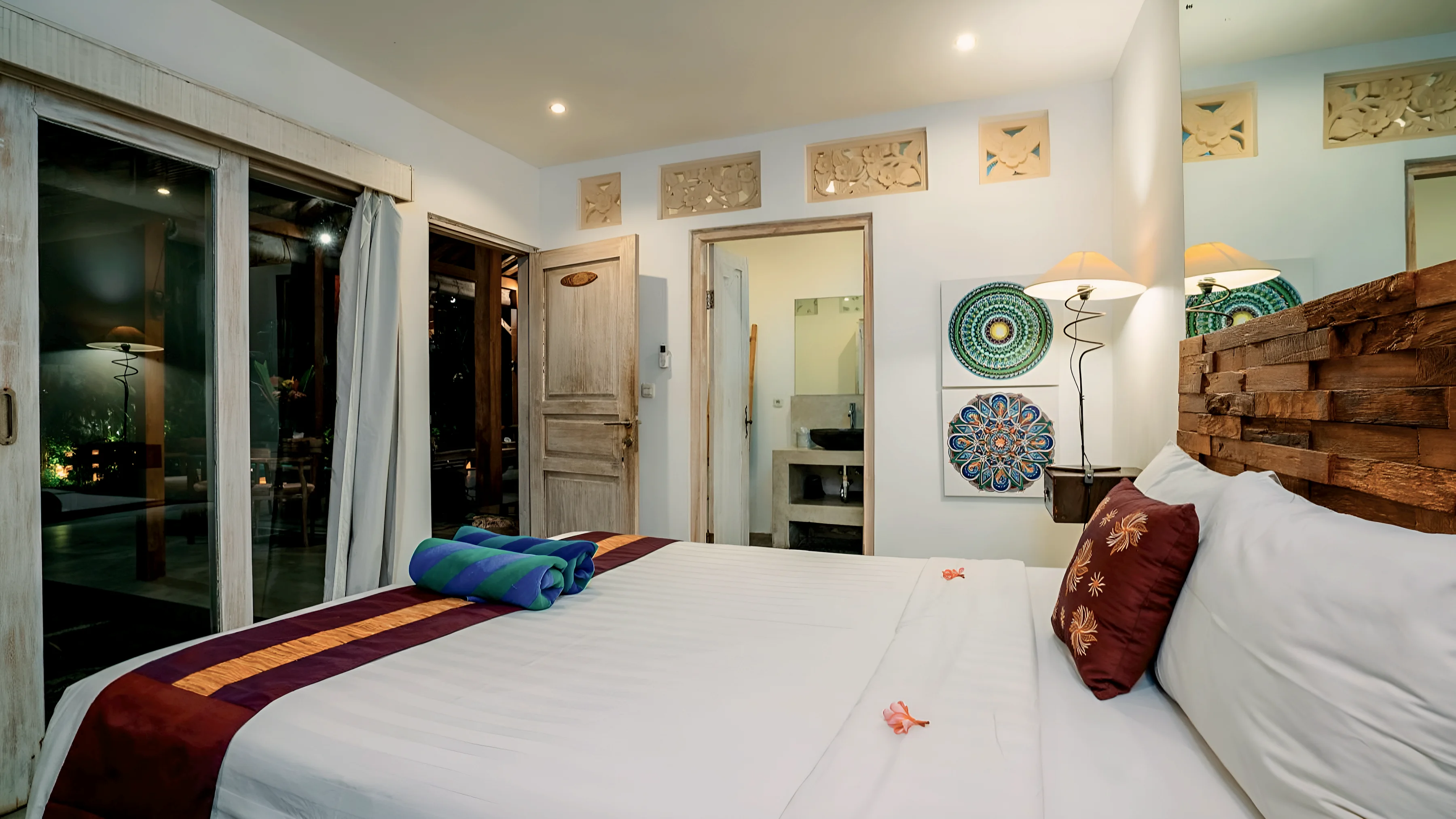 A bedroom with a carved timber headboard and an open door to the bathroom
