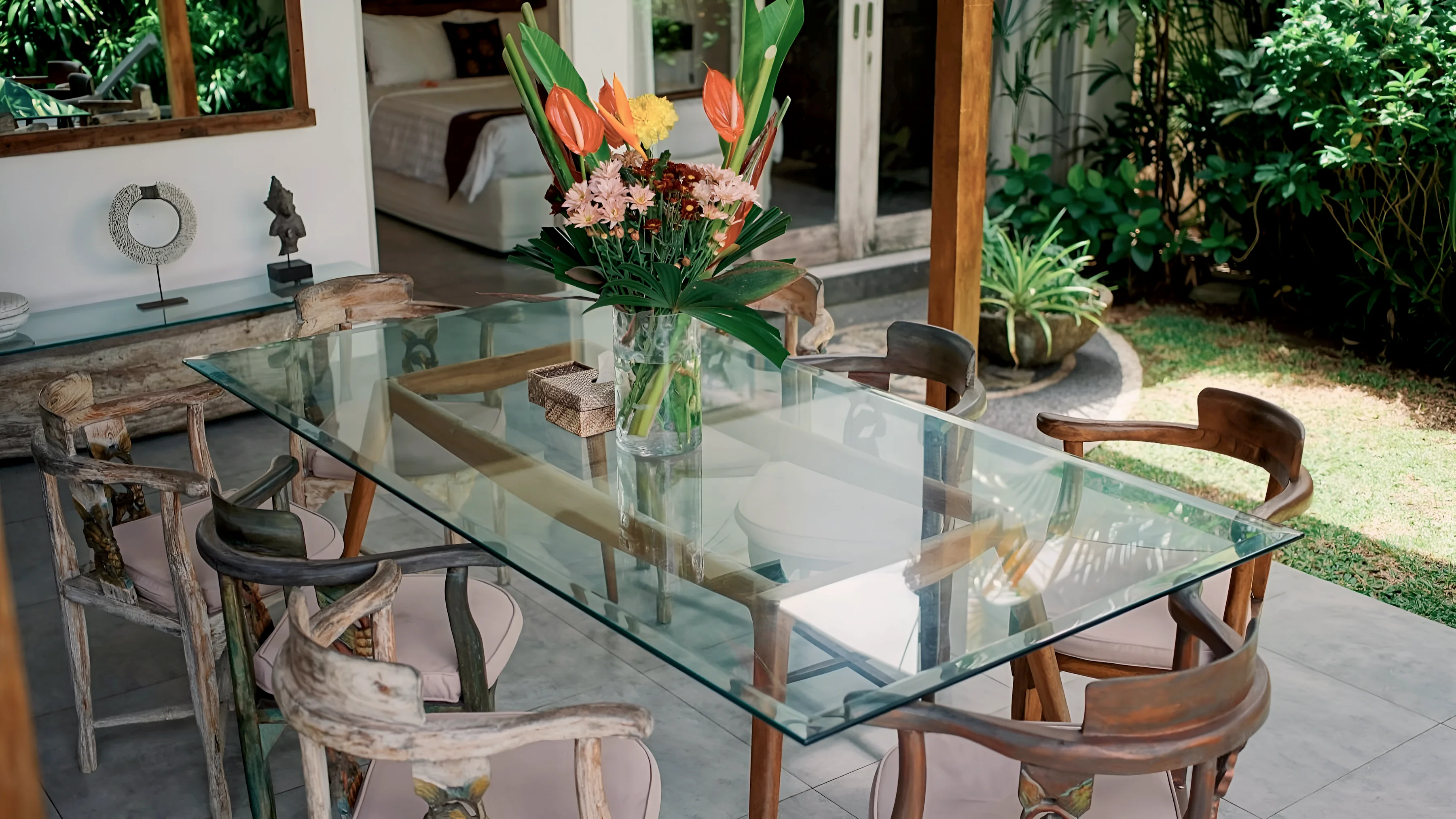 The glass dining table by day, flowers on the table and the garden behind