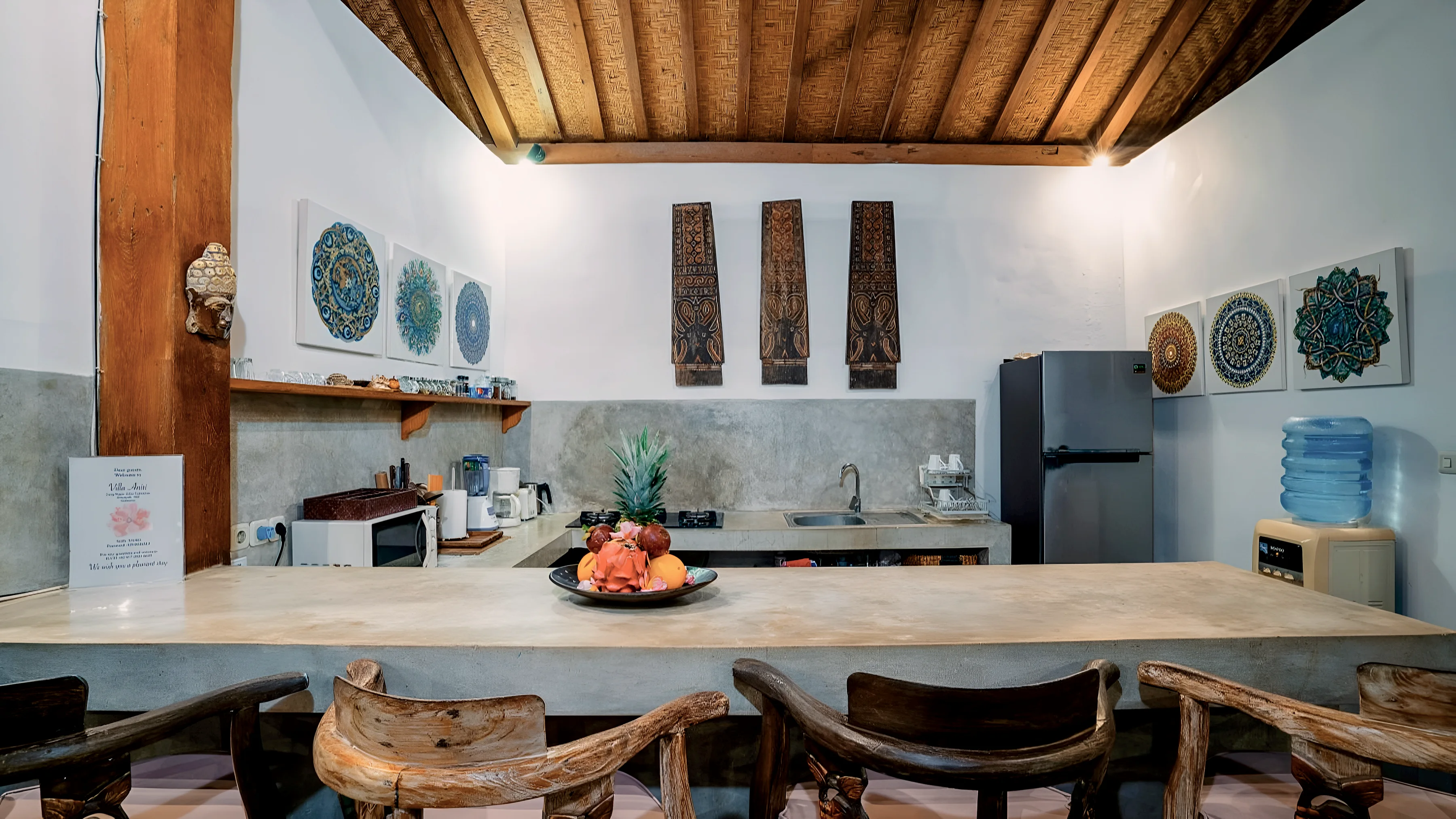 The kitchen bar with stools, a fruit bowl and carved panels on the wall