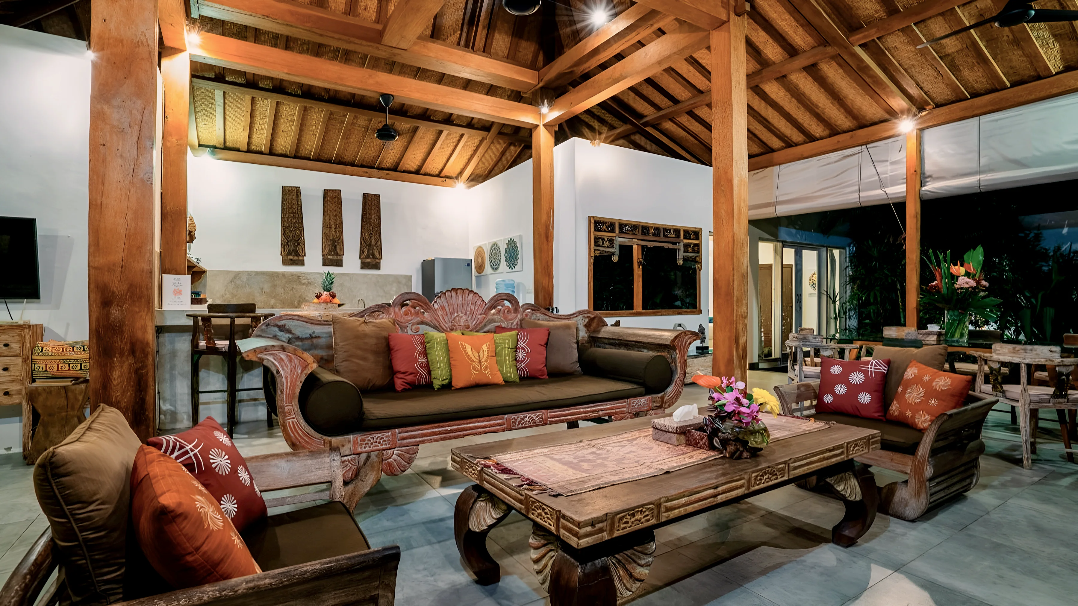 The living pavilion in the evening: carved daybed, cushions and a low table